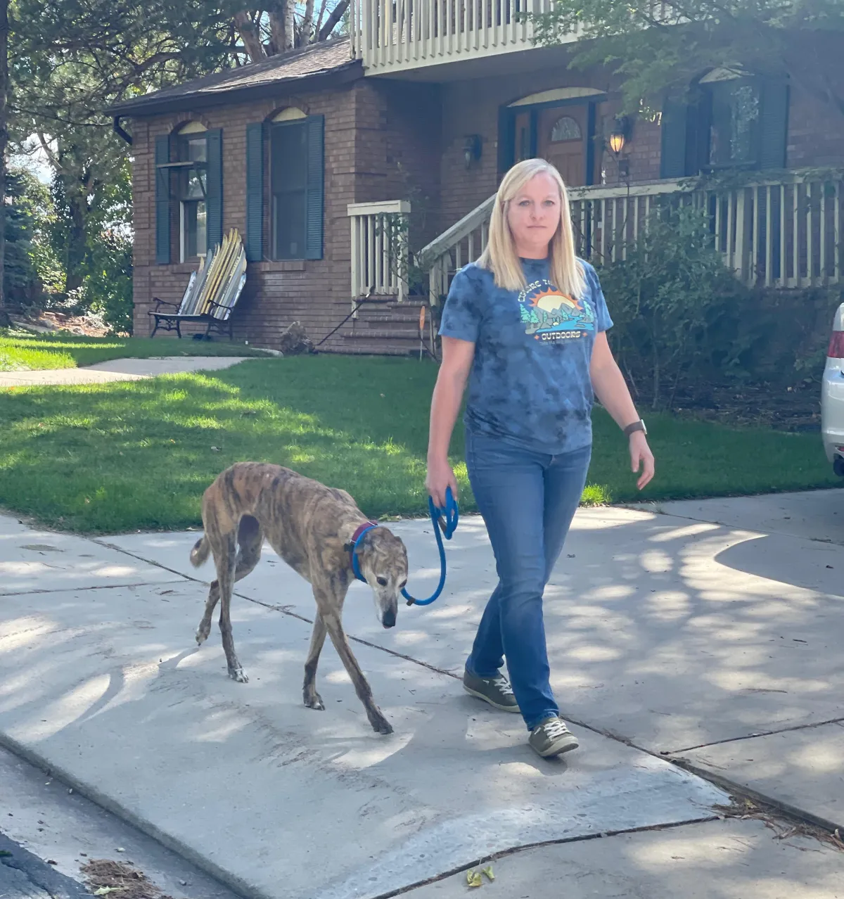 Owner walking her dog on a loose leash outside their home